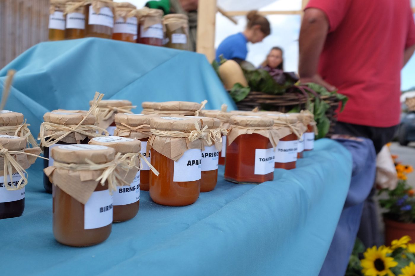 Feine, selbstgemachte Konfitürengläser stehen auf einem Marktstand.