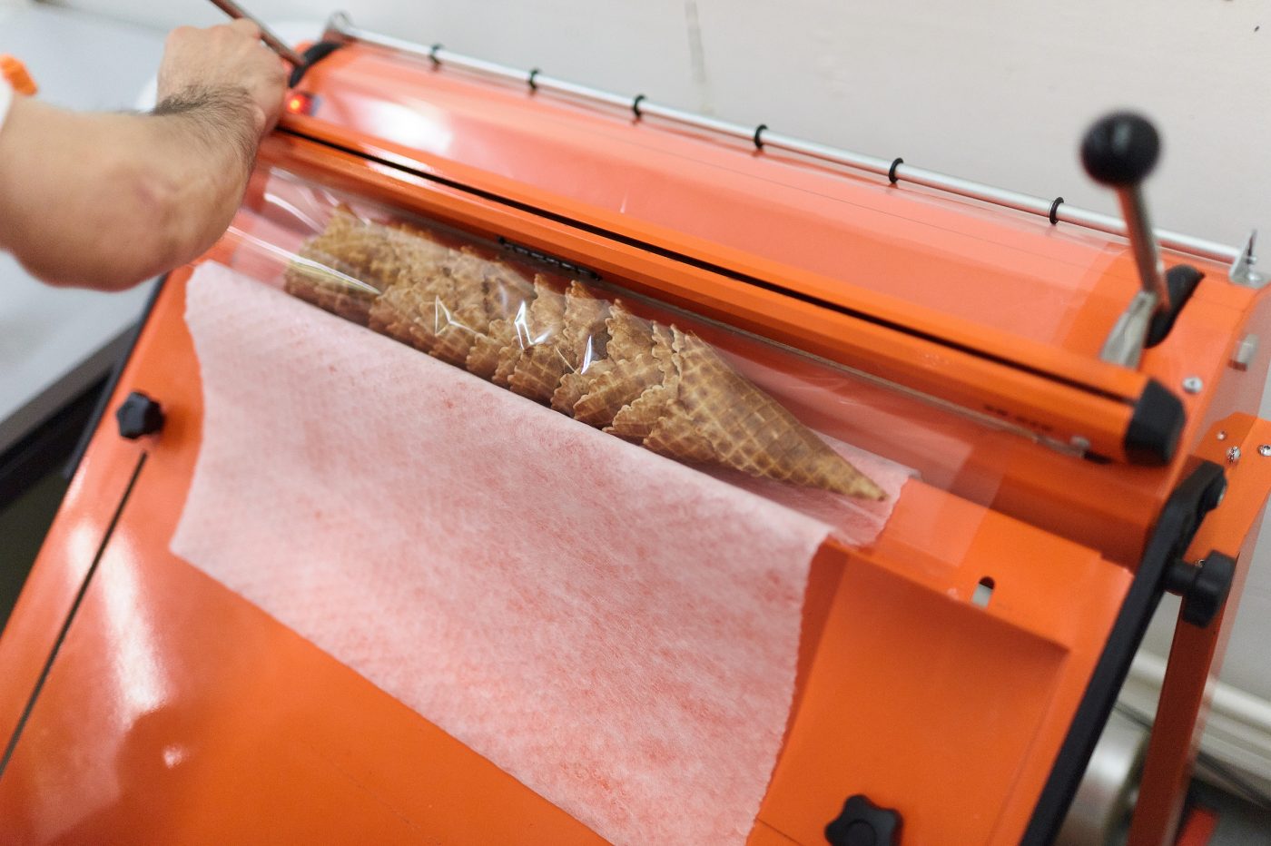 In Folien eingelegte Cornets liegen auf der orangen Verpackungsmaschine bereit zum verschweissen.