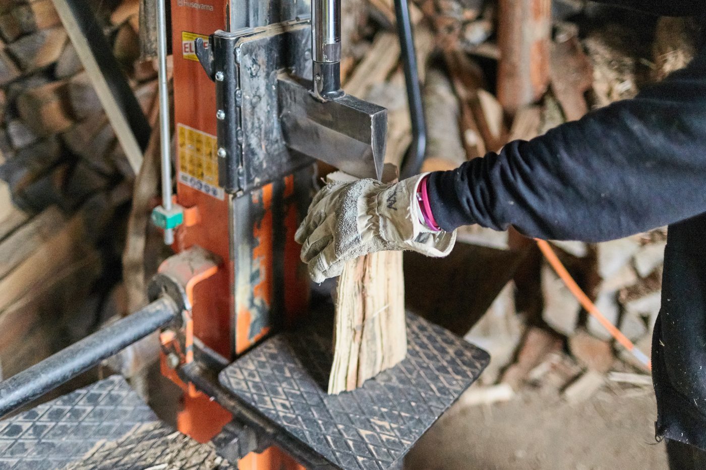 Eine Hand hält einen Holzklotz, der unter der Spaltmaschine für die Spaltung in Position gebracht wird.